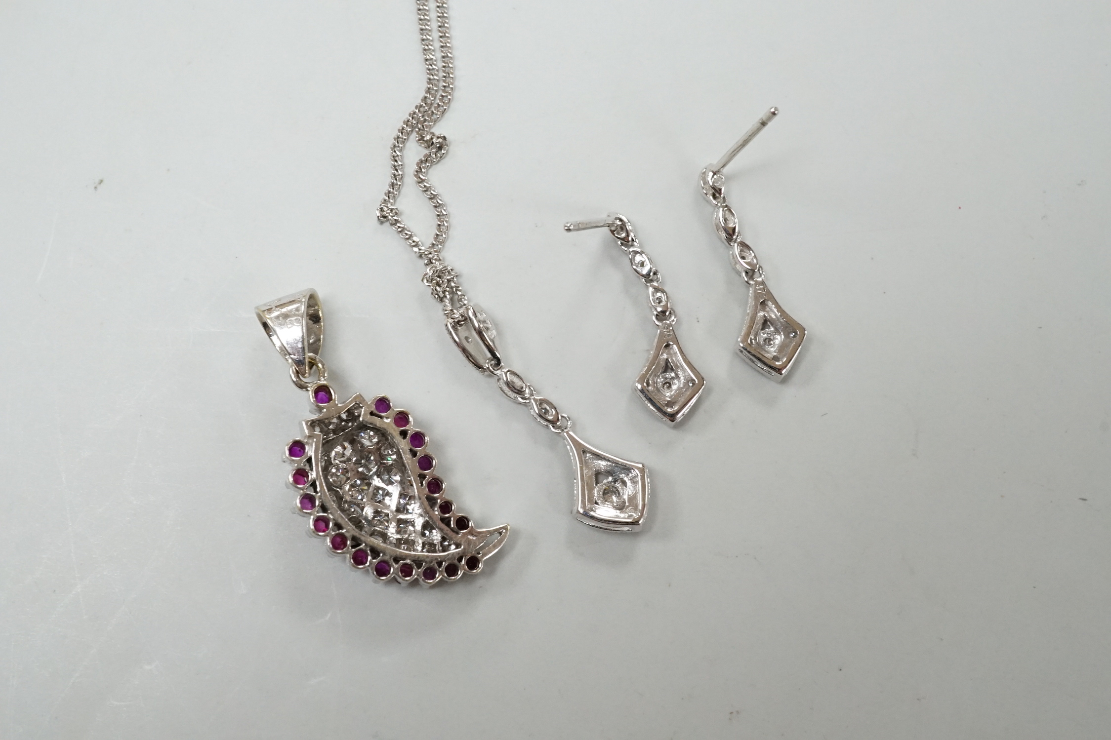 A modern white metal ruby and diamond cluster set drop pendant, modelled as a pear, overall 26mm, together with a modern 375 white metal pendant, 25mm, on a 9ct white gold chain and a pair of matching drop earrings, one